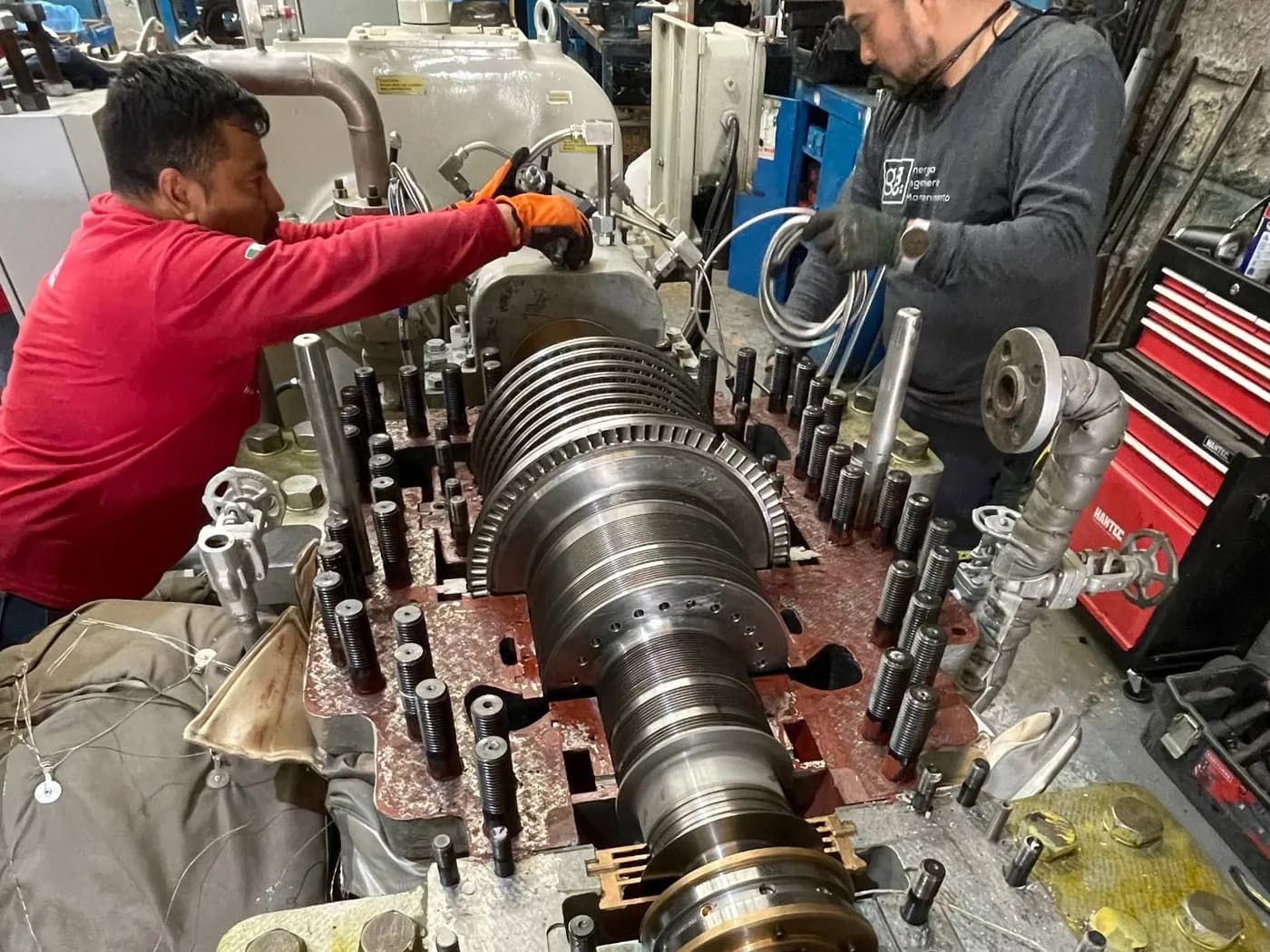 Two Grupo Möller technicians working on the open rotor of a steam turbine in the shop